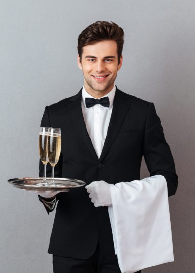 happy-young-waiter-holding-glass-champagne-towel